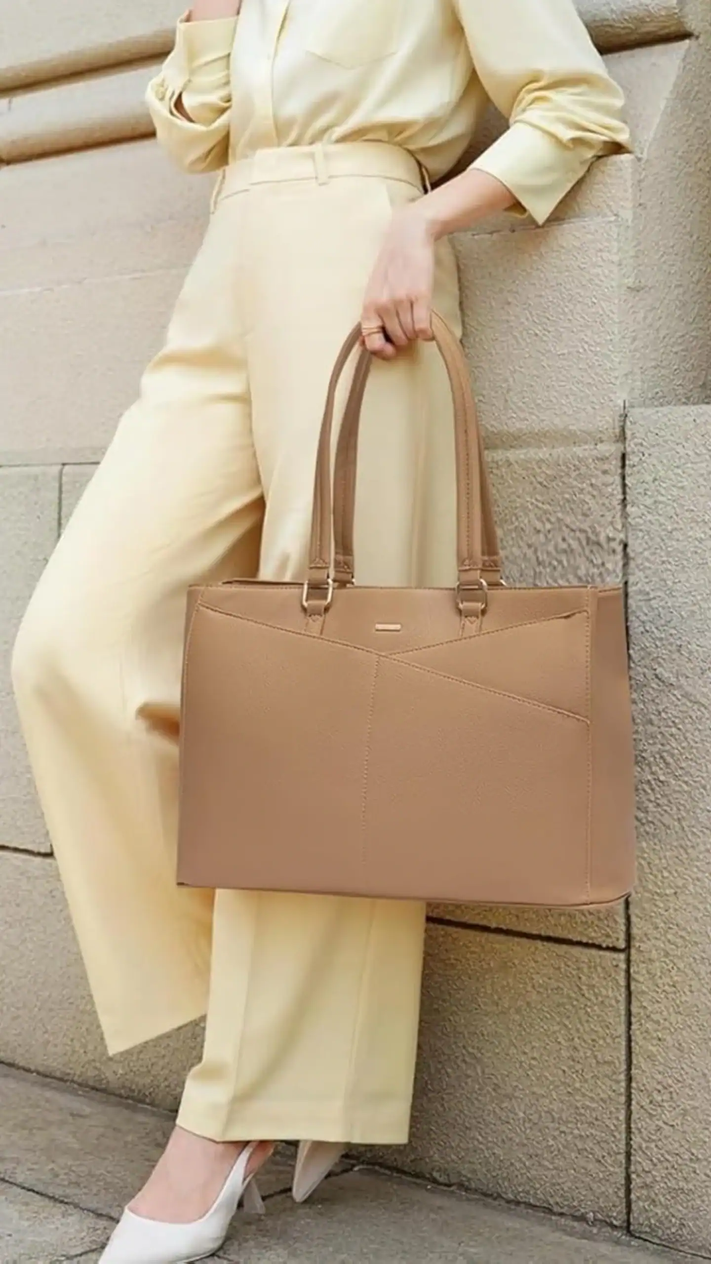 The handbag features a structured tote silhouette, designed for carrying laptops up to 15.6 inches, crafted from durable canvas with a smooth, matte finish. Its warm apricot hue, accented by geometric seams, gives it a contemporary, professional vibe, making it suitable for work or casual outings.