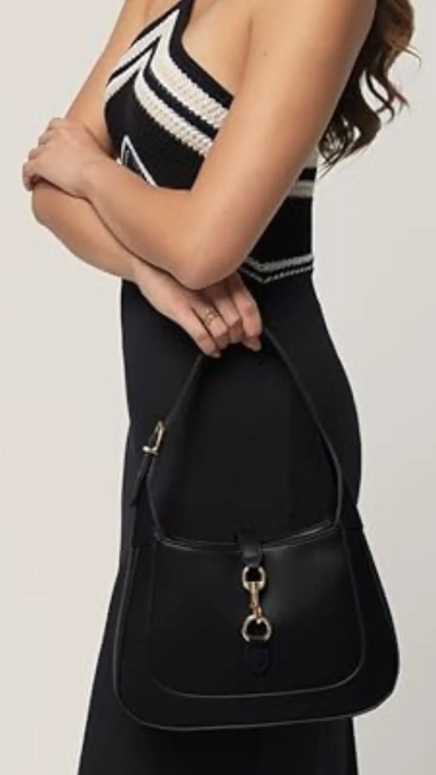 This black shoulder bag features a structured silhouette with a smooth, matte genuine leather texture, complemented by an adjustable strap for versatile styling. Its minimalistic design includes subtle gold-toned embellishments, making it a chic accessory suitable for casual outings or elevated everyday wear.
