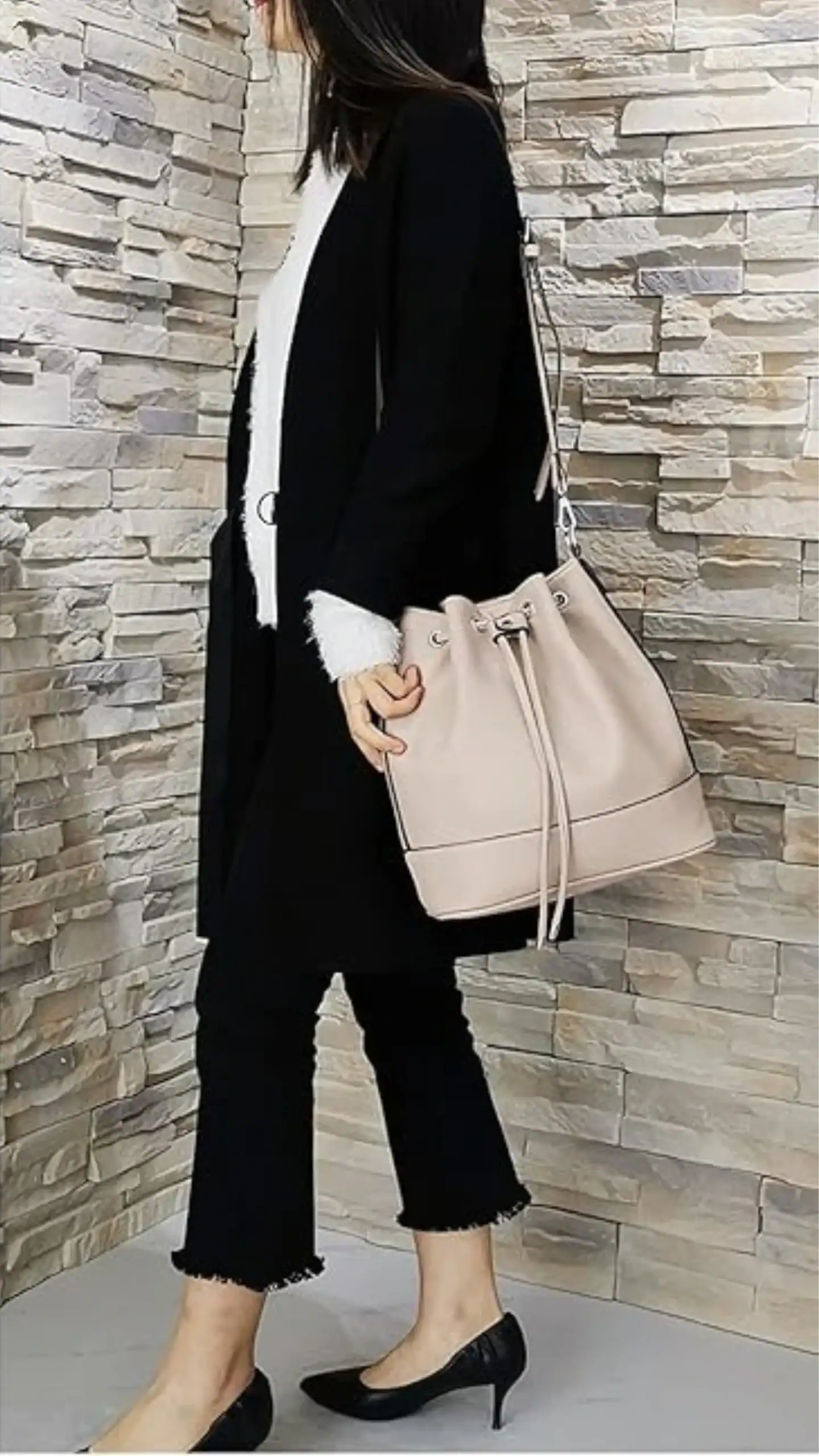 This medium leather bucket bag features a structured silhouette with a soft matte finish, designed with a drawstring closure for added practicality. It comes in a subtle blush hue, complemented by minimalistic design details, making it perfect for casual outings or everyday wear.