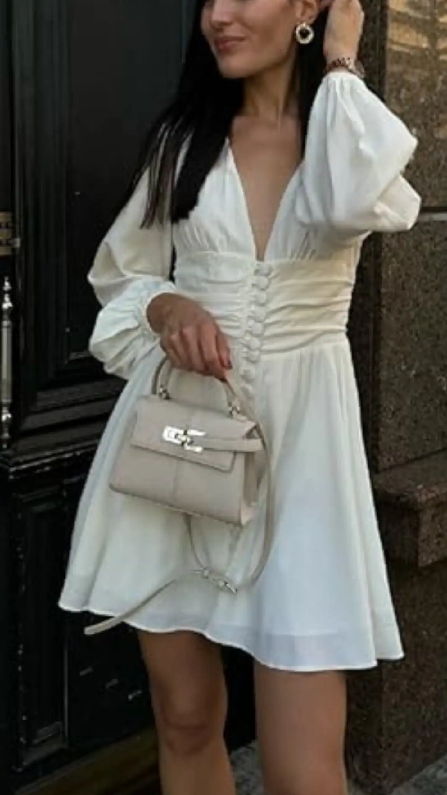 The Elise Top Handle Bag is a chic, structured handbag featuring a petite silhouette reminiscent of the classic Kelly style, crafted from smooth, soft leather that offers a matte finish. In a subtle beige tone, its minimalist design includes a sleek, metal clasp and a detachable strap, making it perfect for both formal occasions and casual outings.