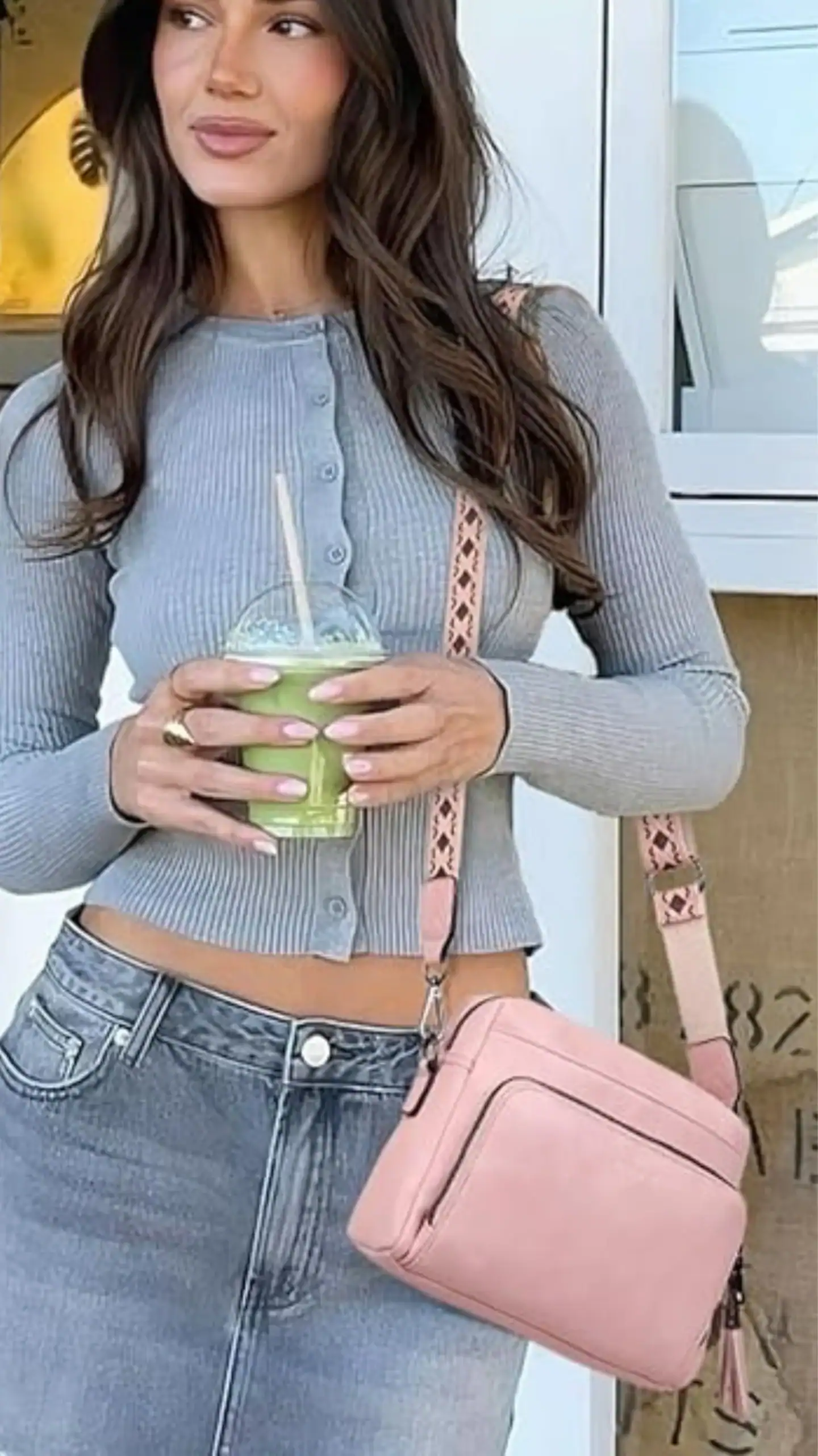 This medium crossbody bag features a structured silhouette with a sleek design, crafted from soft vegan leather that offers a matte texture. The bag is presented in a soft, pastel pink color with subtle top-stitching and a zippered front pocket, exuding a modern and minimalist vibe, making it ideal for casual outings or travel.