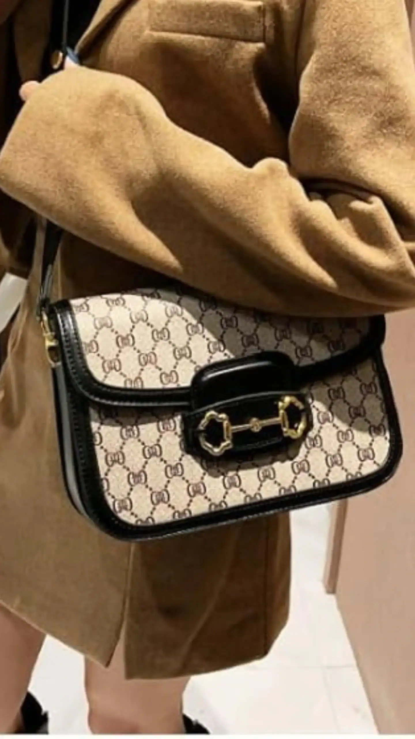 This quilted crossbody bag features a structured silhouette with a soft mini top handle and a gold chain strap, crafted from genuine leather for a luxurious feel. The primary color is a warm beige with a subtle monogram pattern, complemented by black leather trimmings and a decorative gold closure, exuding a classic and chic vibe suitable for casual outings or stylish day events.