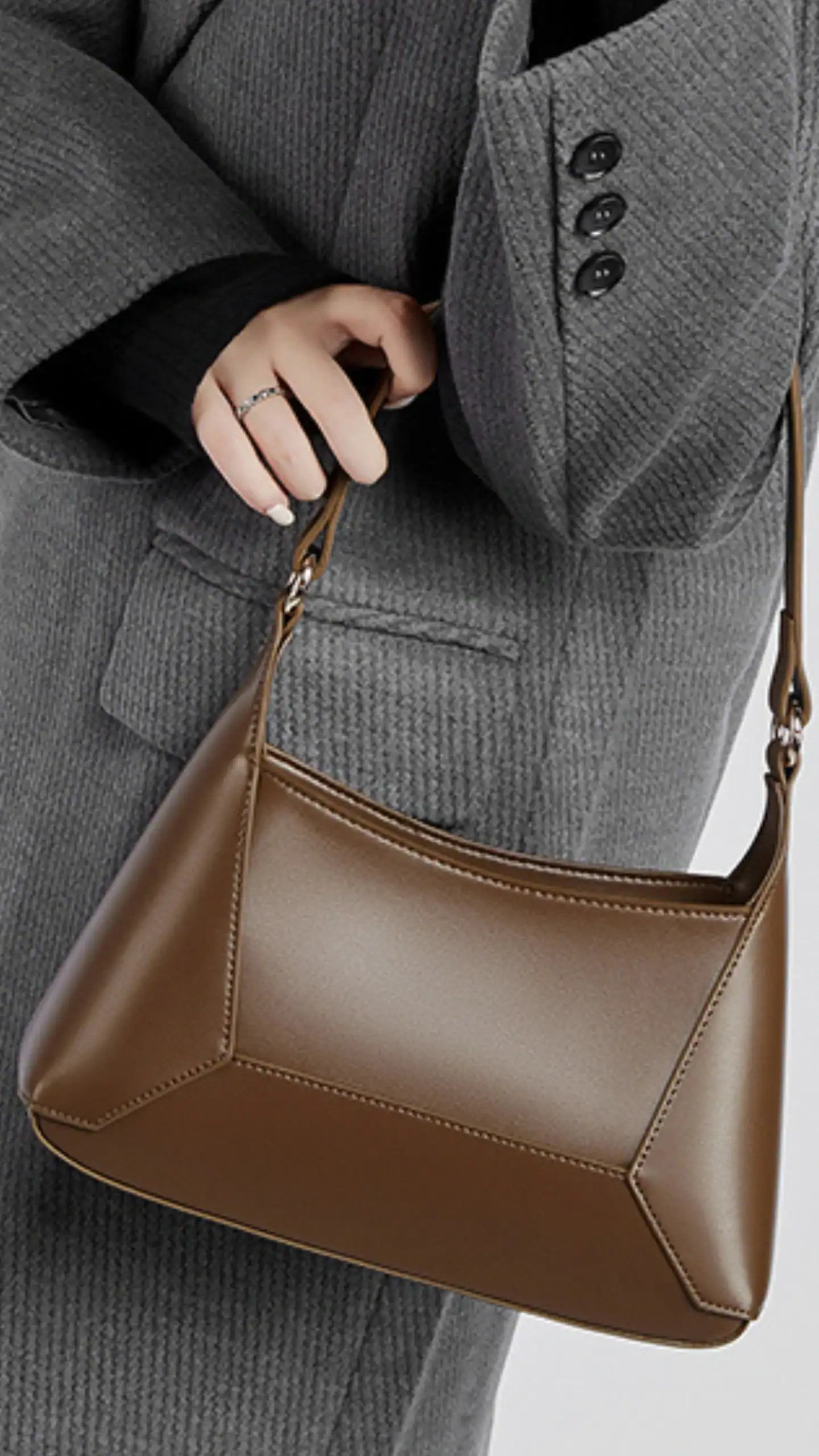 This large vintage hobo tote features a defined, structured silhouette, crafted from smooth vegan leather that offers a matte finish. In a deep, warm brown color, the bag combines minimalistic design with subtle geometric paneling, exuding a chic, modern vibe ideal for casual outings or everyday wear.