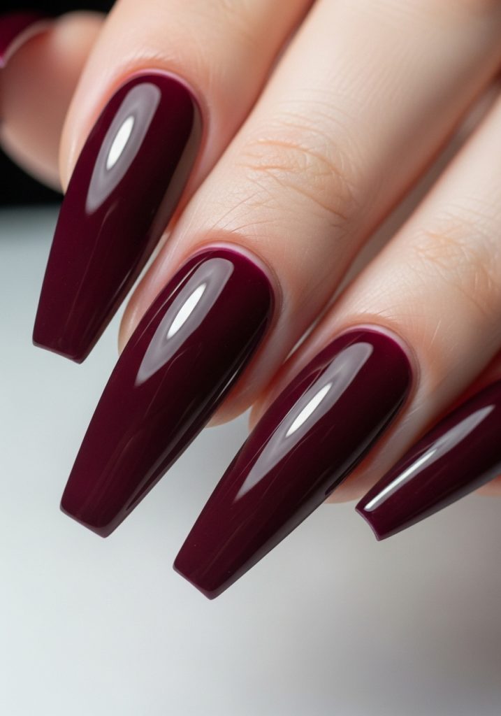 Deep burgundy coffin nails with high-gloss finish and dramatic length