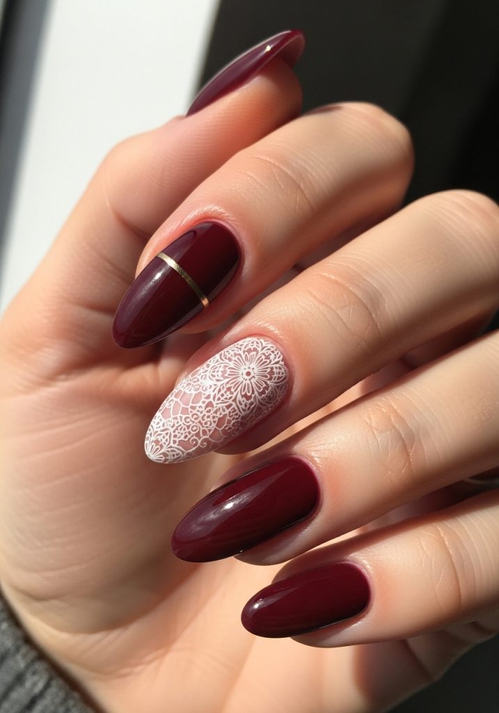 Classy burgundy nails with delicate floral design on accent finger and gold line detail