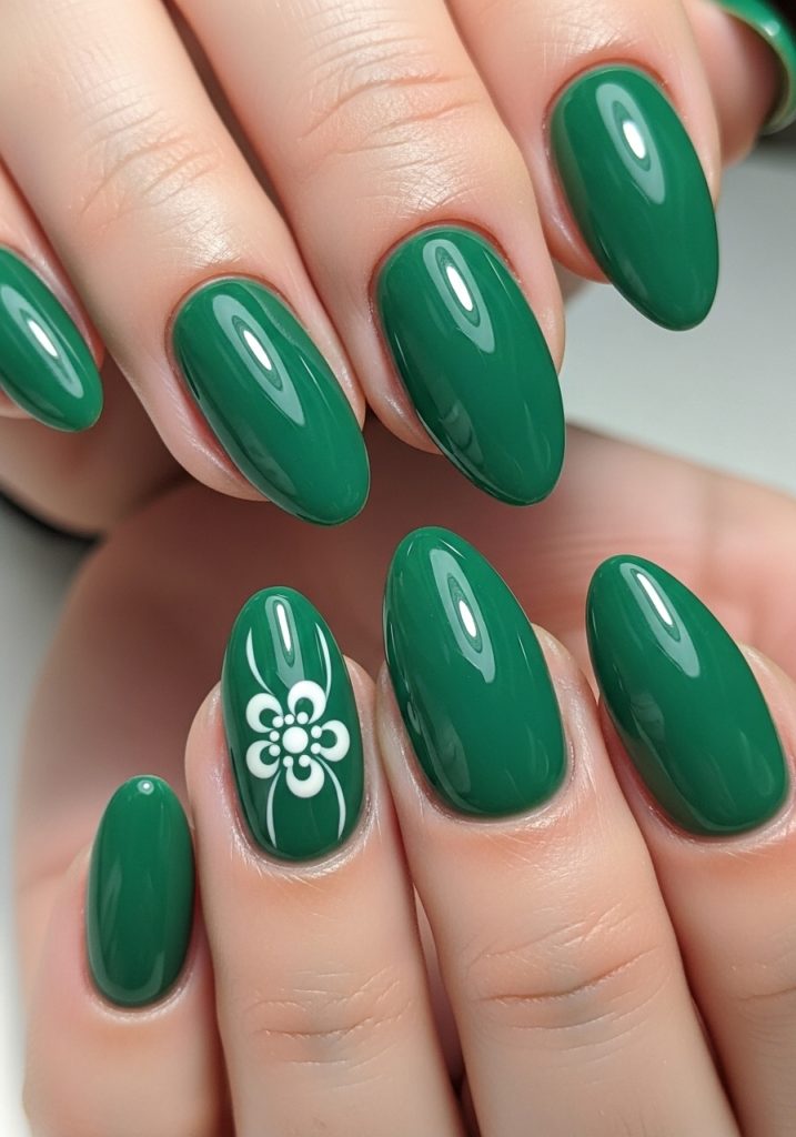 Jade green nails with a small white hand-painted floral design on the ring finger