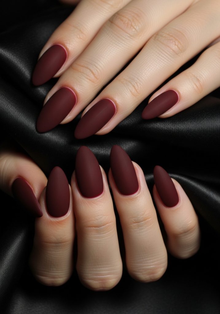 Medium almond nails in dark cherry red matte velvet finish for a chic and glamorous look