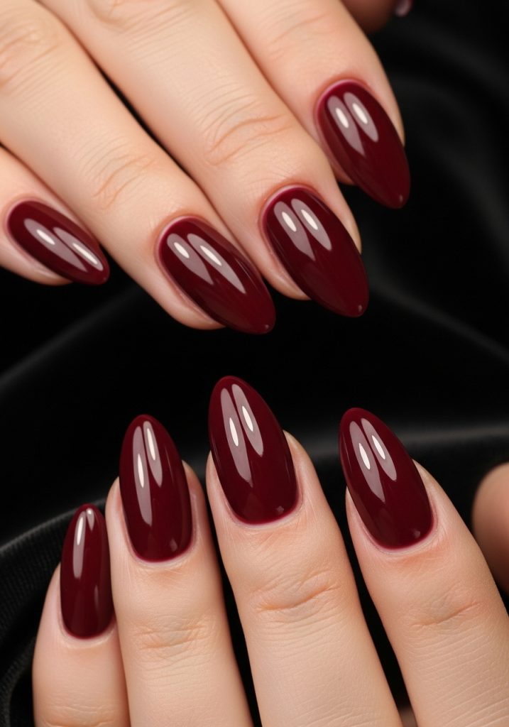 Medium almond-shaped deep burgundy wine red glossy prom nails on black velvet