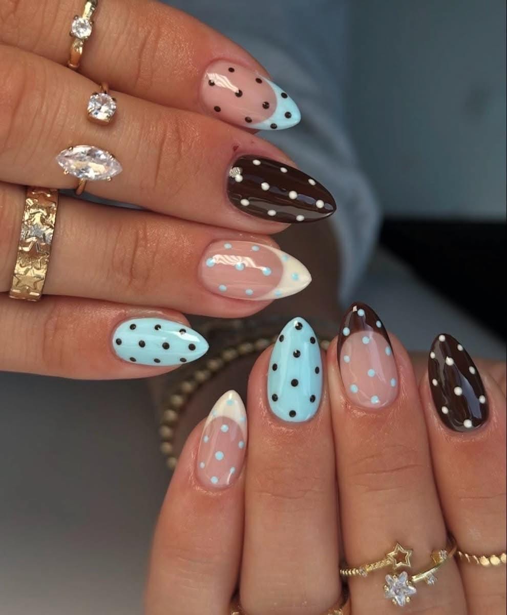 Almond-shaped nails with various blue and brown polka dot designs, including some with French tips.