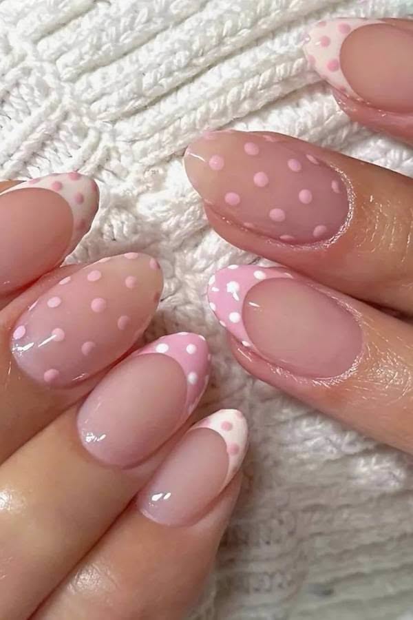 Numerous oval nails with pink and white polka dot designs on a soft white background.