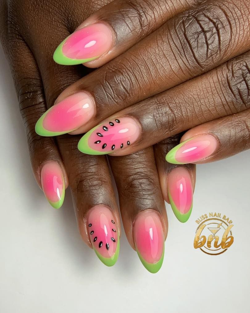 Close-up of a person's hands with watermelon-themed nails. Several nails have pink-to-clear ombré with green tips, and two…