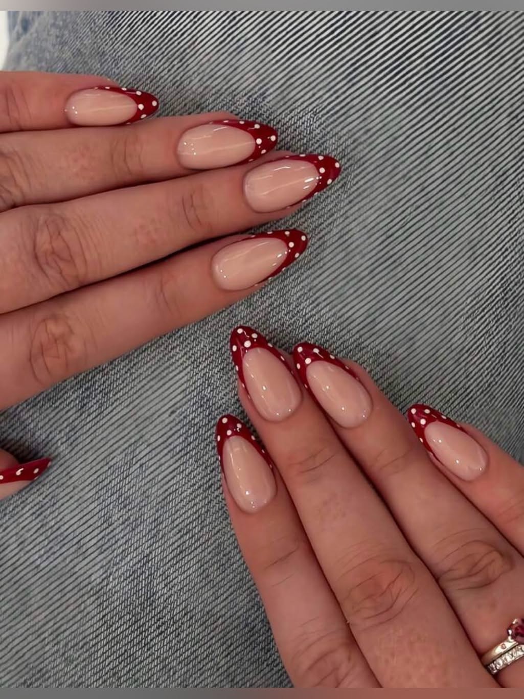 Almond-shaped nails with red French tips with white polka dots