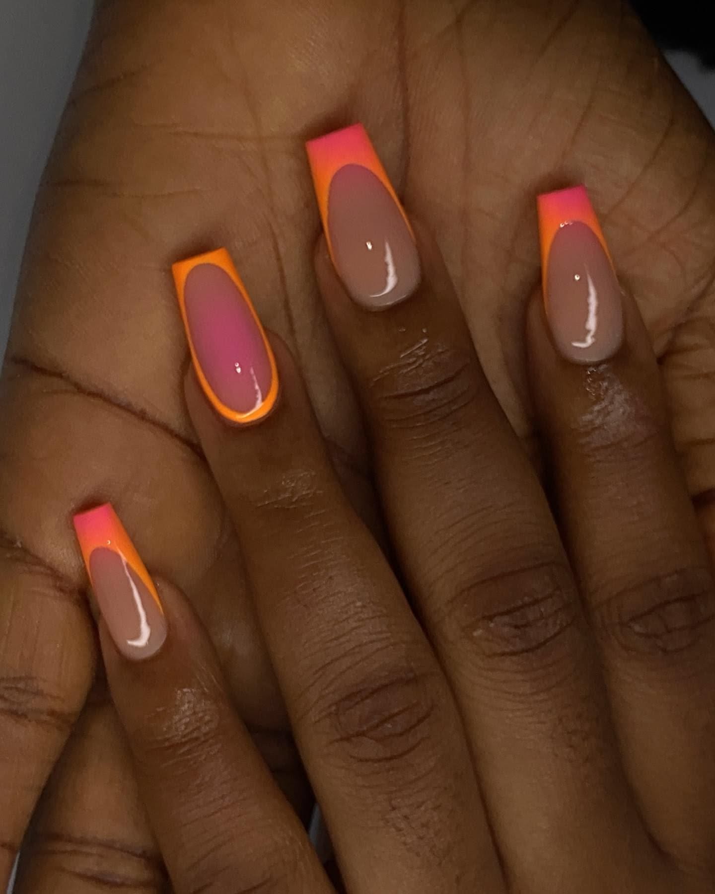 Close-up of a hand with long, square-shaped nails featuring a bold coral and orange French tip design over a clear base.