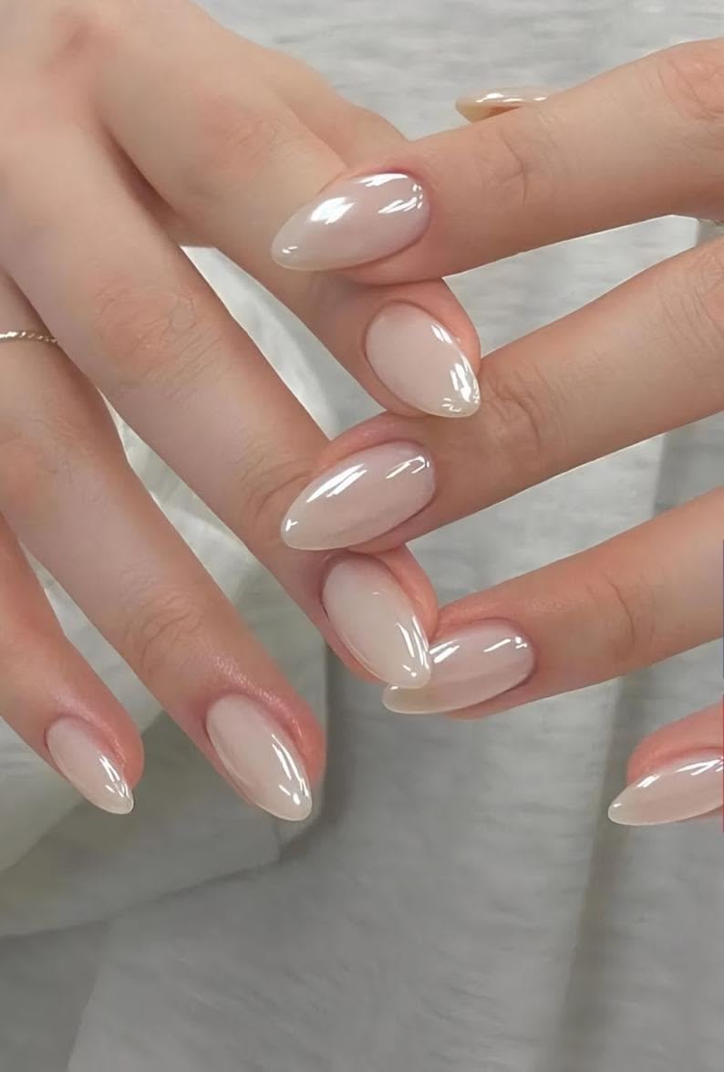 Close up of a person's hands with almond-shaped nails in a neutral iridescent pearl finish.