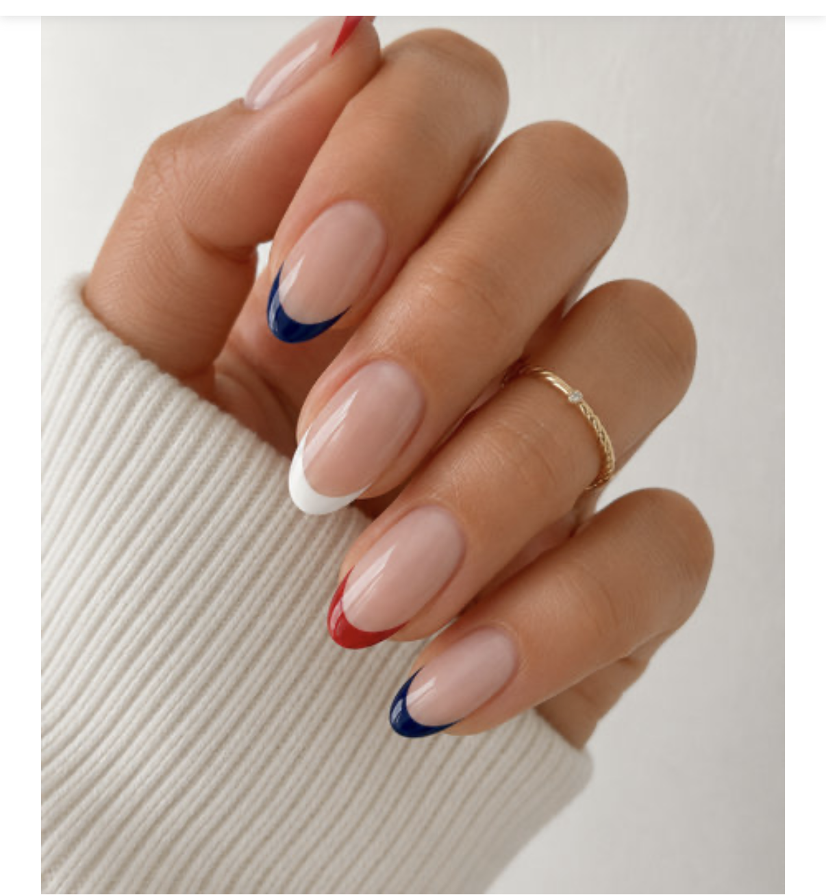 Close-up of a hand with various French manicured nails, each with a different colored tip in red, white, or blue.