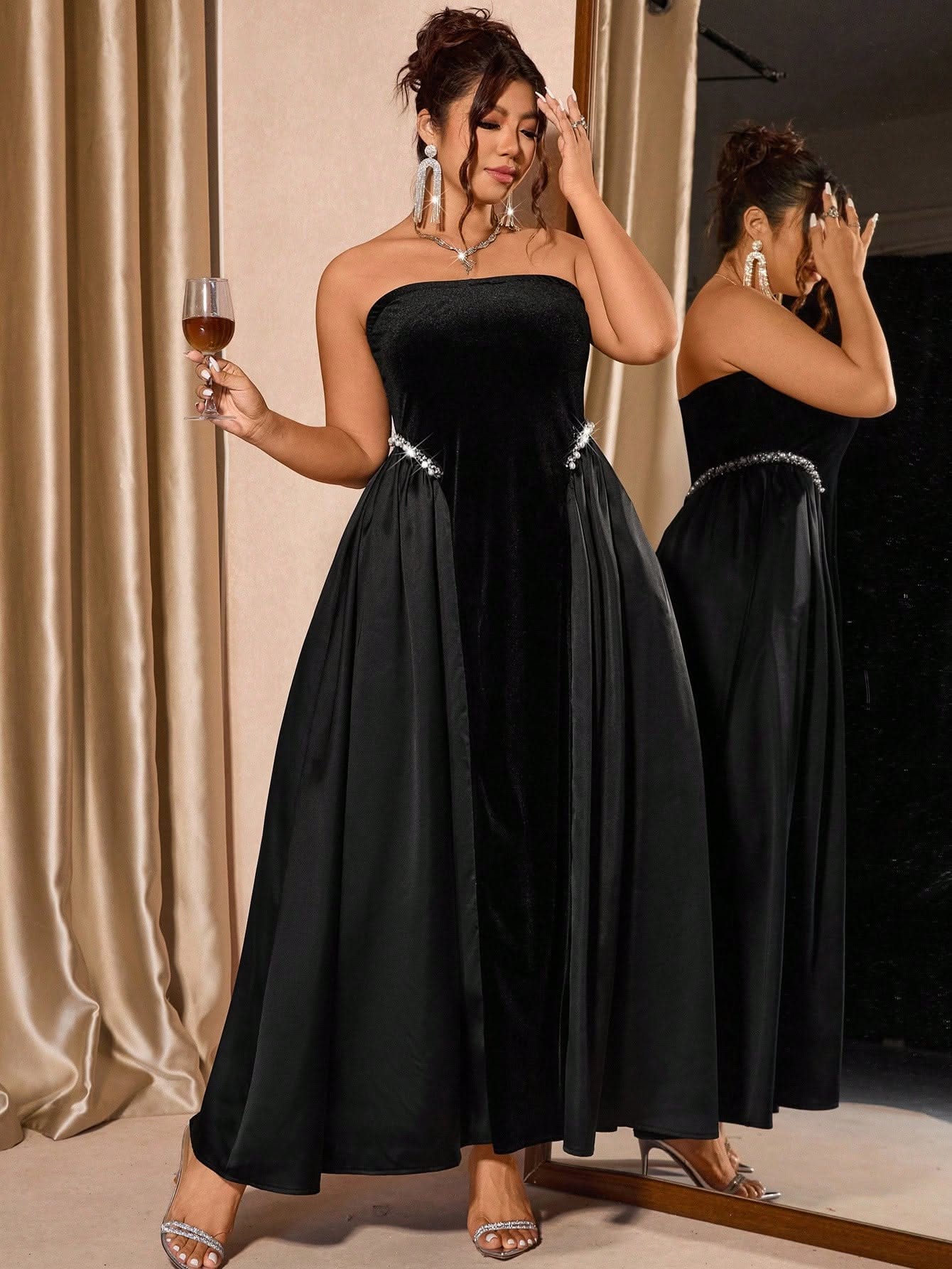 Woman in a strapless black velvet and satin gown with rhinestone embellishments at the waist, holding a glass.